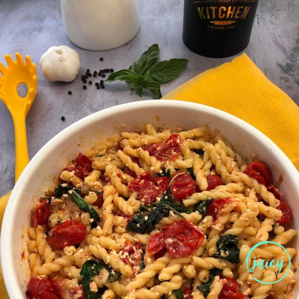 A large bowl of baked feta pasta - with grape tomatoes, fresh basil, garlic, baked melted feta cheese.