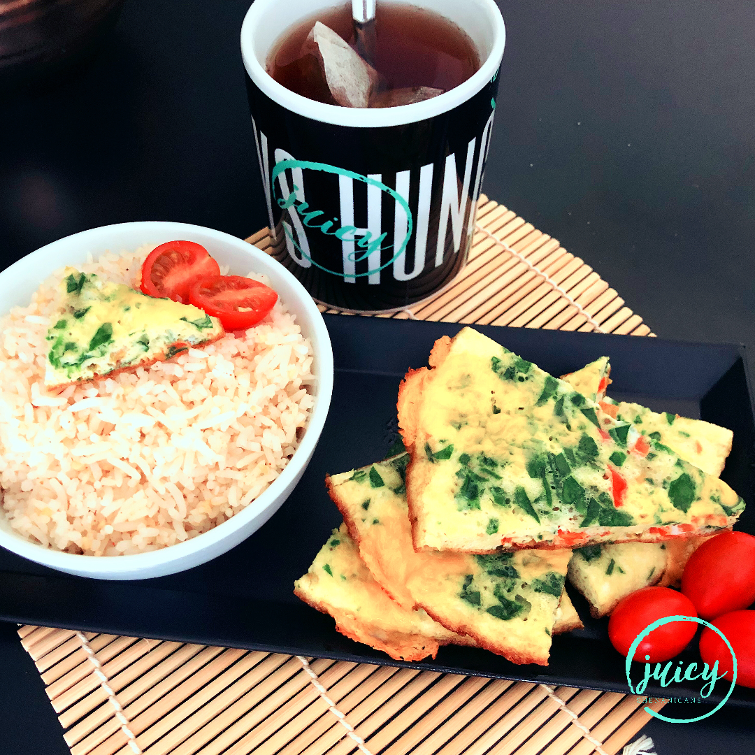 breakfast platter that includes spinach tomato omelette, cut into triangle pieces, garlic rice and fresh grape tomatoes, with hot tea in a mug.