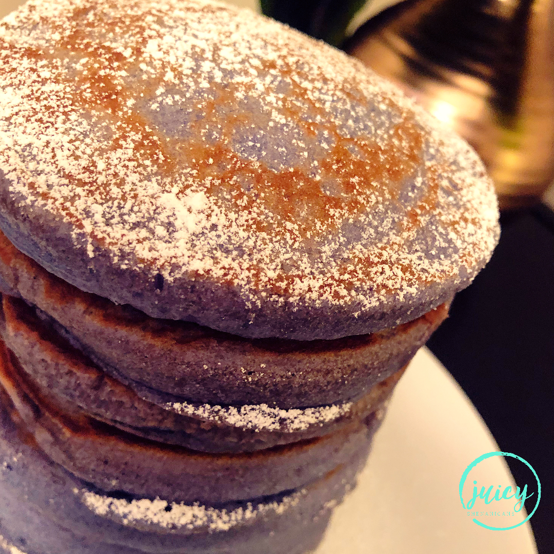 Fluffy Ube Pancakes stacked high with icing sugar sprinkled over the rich and vibrant purple colour from the ube